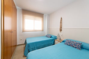 Un dormitorio con dos camas, un armario de madera, una ventana con persianas y un adorno en la pared.