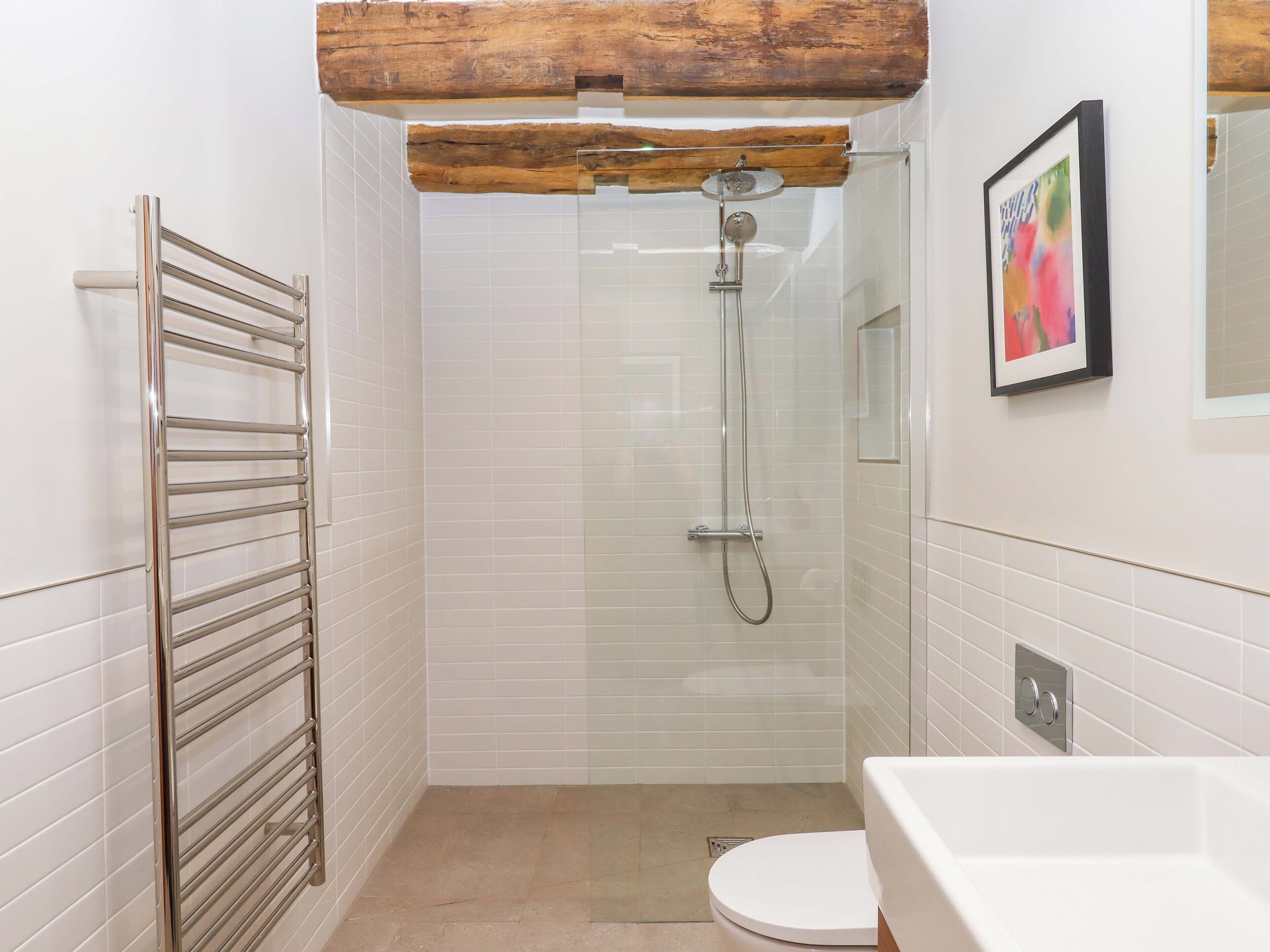 Un baño con ducha separada por mampara de cristal, inodoro blanco y bañera.