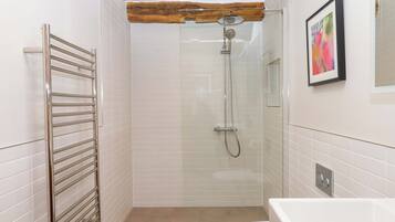 Un baño con ducha separada por mampara de cristal, inodoro blanco y bañera.