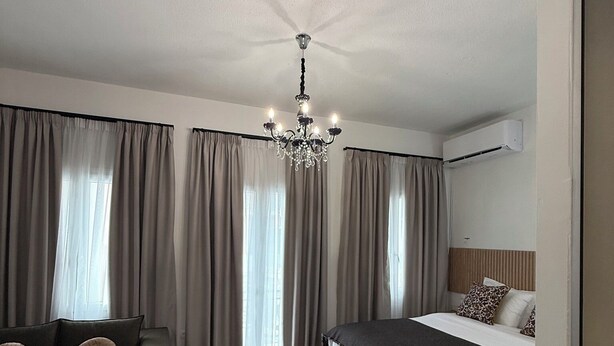 A modern hotel room with a bed, a sofa, a small table, and a chandelier.
