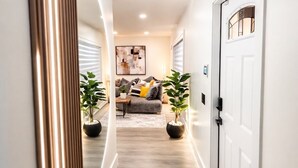 A hallway with a modern design, featuring a large mirror and a door on the right.