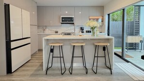 A modern kitchen with a central island, bar stools, and a microwave.
