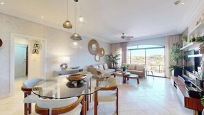 Un salon moderne avec une table à manger en verre, des canapés et un téléviseur.