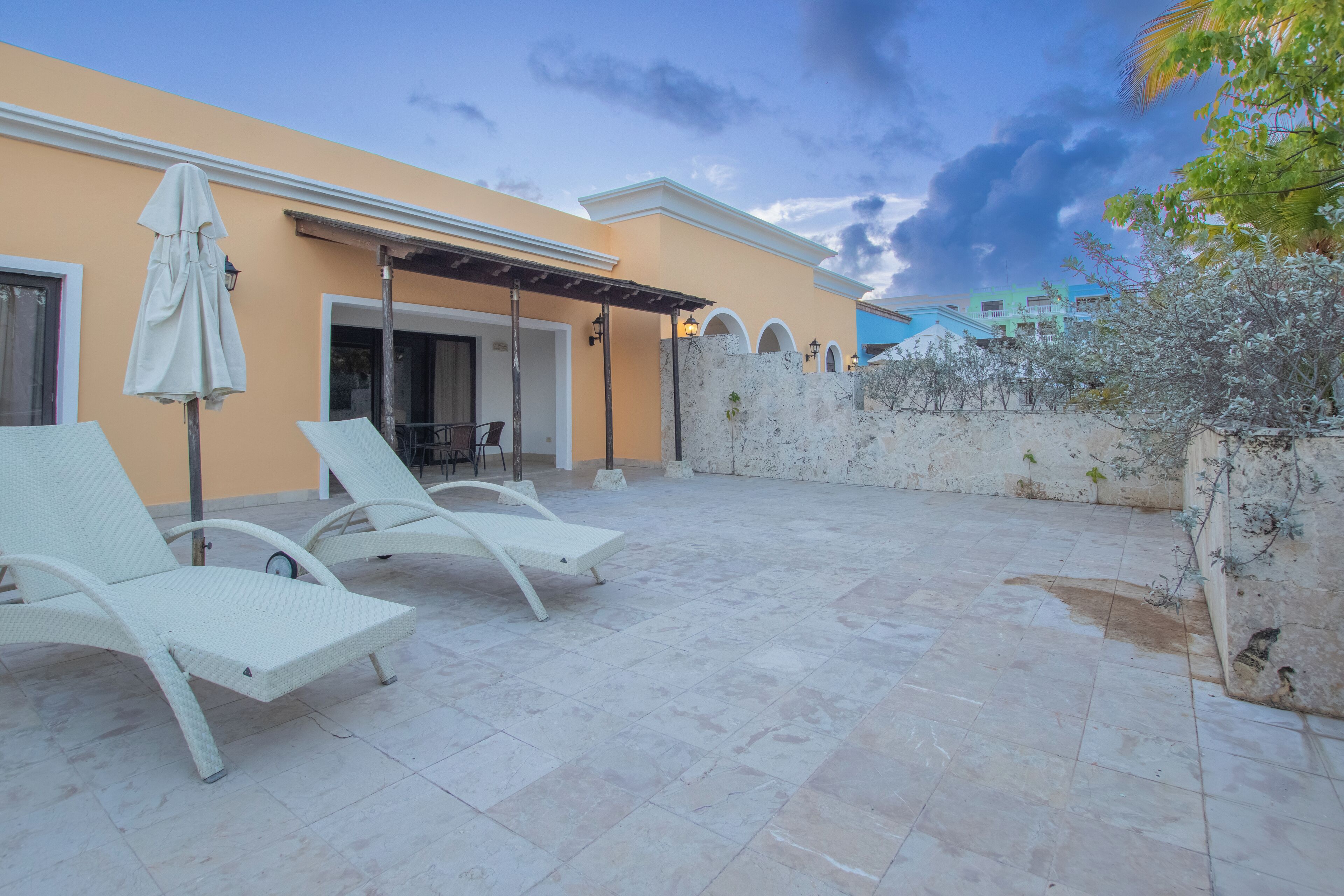 A patio area with two white lounge chairs and a covered seating area.