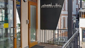 Une entrée d’immeuble avec une porte en verre, une porte en bois et une enseigne indiquant « BREISGAU LOFTS ».