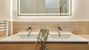 A modern bathroom with a large mirror, two sinks, and a wooden vanity. - Elegant Apartment With Buttes-chaumont Park (Paris)