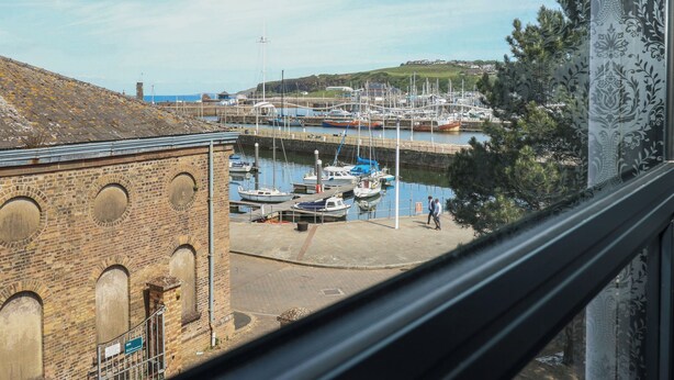 A harbor with boats docked, a brick building, and a view of the sea. - Quayside Apartments (Whitehaven)