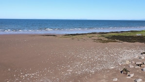 A beach with a clear sky and calm sea. - Harbourside Apartments (Whitehaven)
