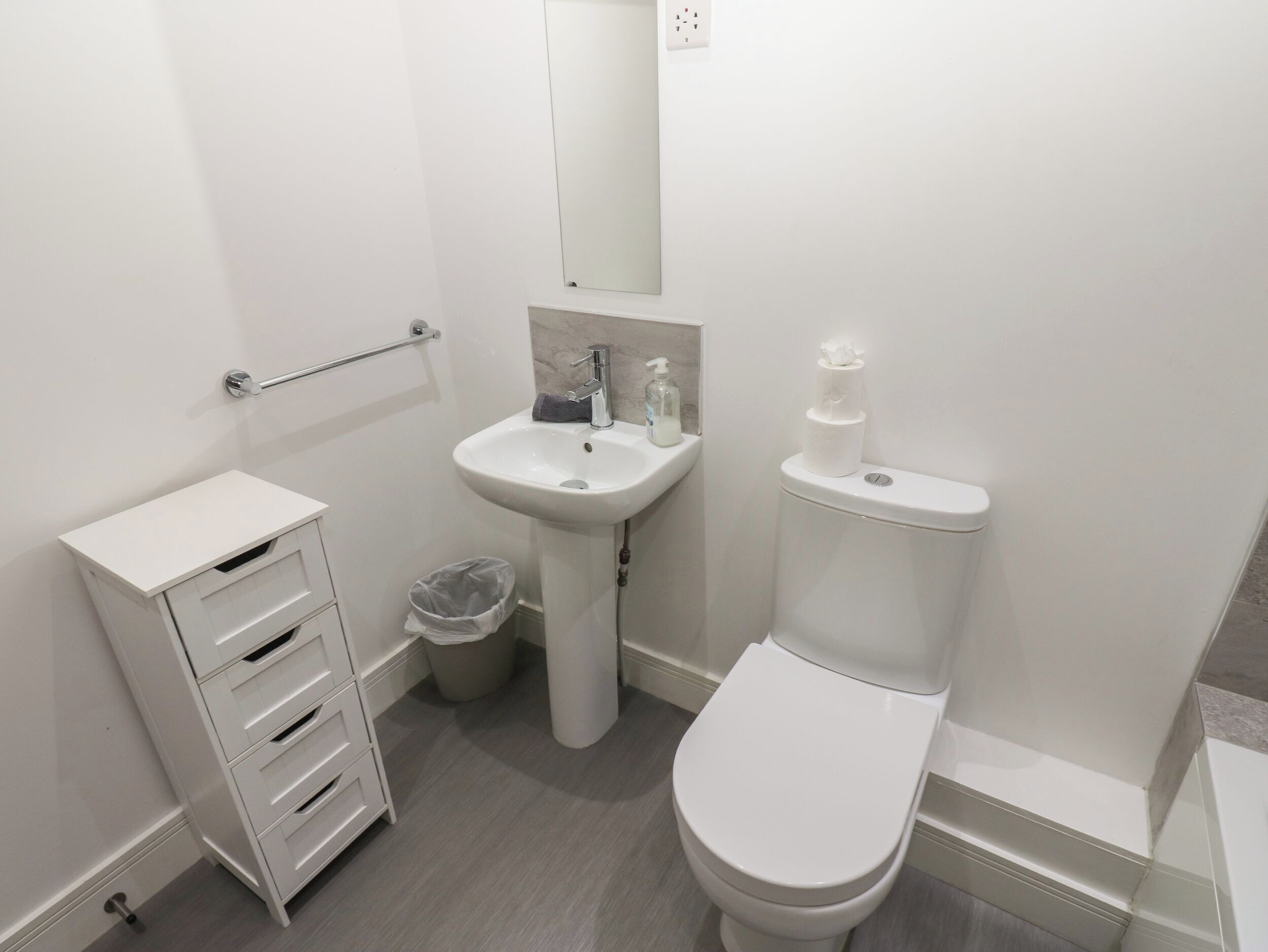 Un baño moderno con un lavabo, inodoro y mueble de almacenamiento blancos.