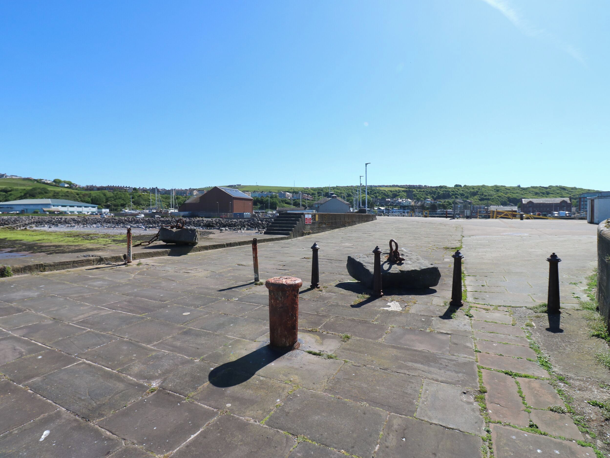 A stone-paved area with bollards and a large rock sculpture.