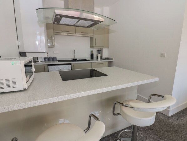A modern kitchen with a built-in microwave, a sink, and a glass-fronted range hood.