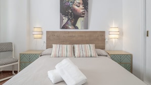 A neatly made bed with a pillow, a bedside table with a lamp, and a chair. - Apartment 'Playa Regla' with Balcony, Wi-Fi and Air Conditioning (Chipiona)