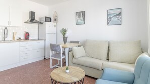 A modern kitchen with white cabinets, a dining area with a table and chairs, a sofa, and two framed pictures on the wall. - Apartment 'Playa Regla' with Balcony, Wi-Fi and Air Conditioning (Chipiona)