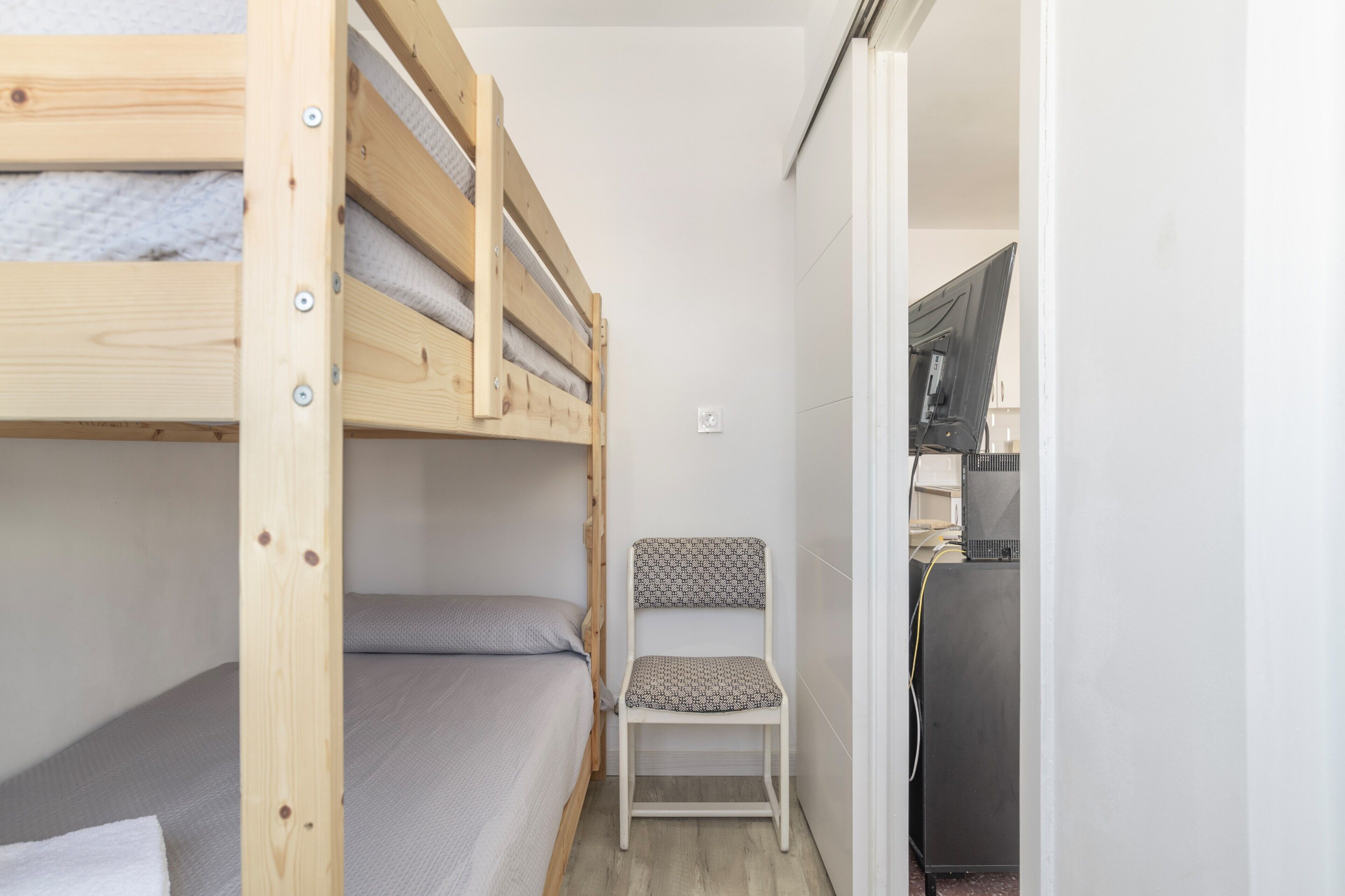 Una stanza piccola e compatta con un letto a castello, una sedia e un angolo cottura.