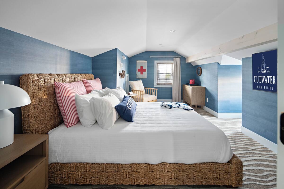 A bedroom with a large bed, a wooden headboard, a bedside table with a lamp, and a nightstand.