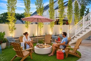 A patio with wooden chairs, a round table, and a red umbrella.