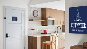 A modern kitchen with wooden cabinets, a microwave, and a red kettle on the counter. - Cutwater Inn & Suites (Newburyport)