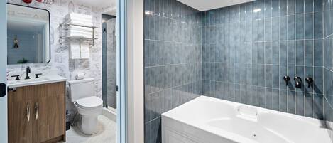 Un baño moderno con una bañera grande, un inodoro y un tocador con espejo.
