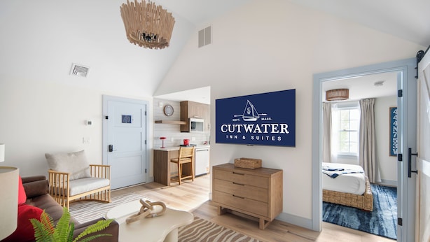 A modern hotel room with a kitchenette, a dining area, and a bedroom with a bed and a window. - Cutwater Inn & Suites (Newburyport)