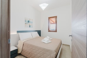 Une chambre à coucher comprenant un lit, une table de chevet, une lampe fixée au mur et une fenêtre donnant sur un paysage agréable.