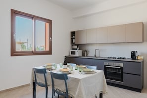 A compact kitchen with a dining area, a built-in oven, and a window with a view.