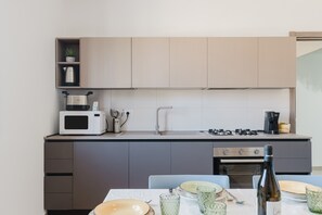 A modern kitchen with a microwave, stove, and oven. There is a dining table with plates and glasses.