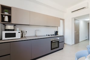 A modern kitchen with a microwave, stove, and oven, a sink, and a small plant on the countertop.