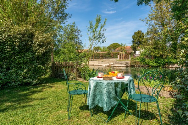 A table with a tablecloth, two chairs, and a basket of fruit.