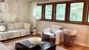 Una sala de estar moderna con un sofá, un sillón y una mesa de centro con un tazón.