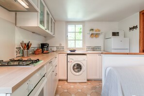 Une cuisine de taille réduite équipée d’un lave-linge, d’une cuisinière et d’un réfrigérateur.