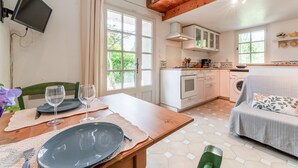 Una cocina con una mesa de comedor preparada para dos personas, un sofá y un televisor montado en la pared.