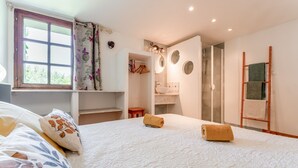 Un dormitorio con cama, ventana, armario, baño y ducha.