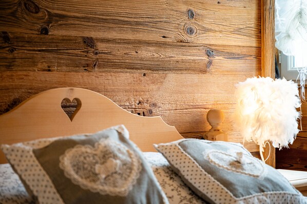 Une tête de lit en bois ornée d’un motif en forme de cœur, d’une décoration en plumes blanches et de coussins à motifs.
