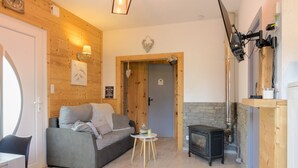 Ein gemütliches Zimmer mit einer Couch, einem kleinen Tisch, einem Kamin und einer Holzwand.