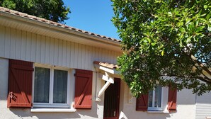 A single-story house with a white exterior, red shutters, and a tiled roof. - Quiet house near the lake, ideal for families (Sanguinet)
