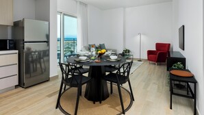 A modern kitchen with a stainless steel refrigerator and a dining area with a round table and black chairs. - Maison Privee – Chic Yas Island Escape w/ Iconic Ferrari World Vws (Abu Dhabi)
