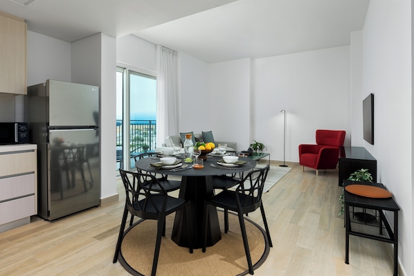 A modern kitchen with a stainless steel refrigerator and a dining area with a round table and black chairs. - Maison Privee – Chic Yas Island Escape w/ Iconic Ferrari World Vws (Abu Dhabi)