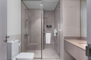 A modern bathroom with a glass-enclosed shower, a toilet, and a sink. - Maison Privee – Chic Yas Island Escape w/ Iconic Ferrari World Vws (Abu Dhabi)