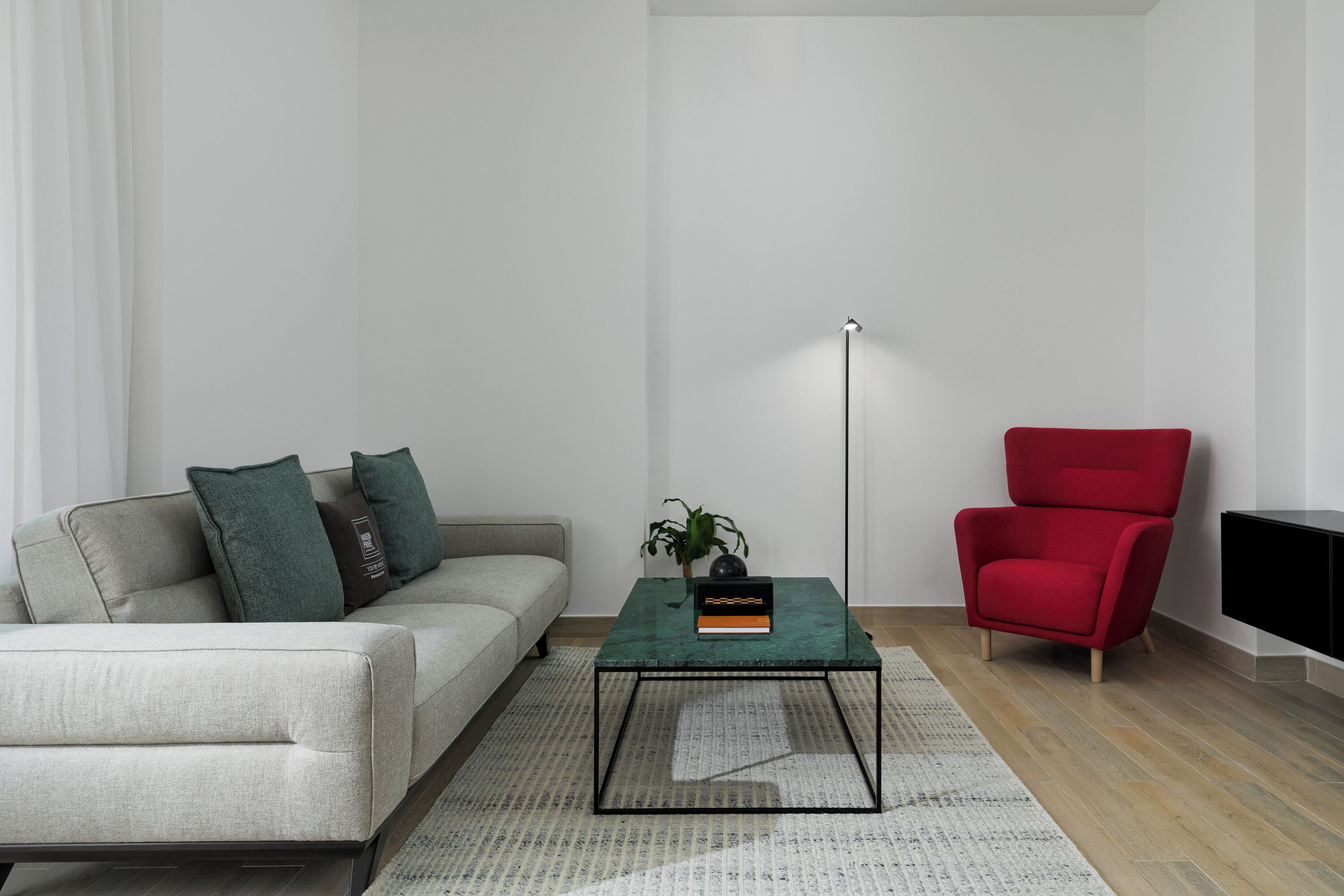 A modern living room with a sofa, a red armchair, a coffee table, and a floor lamp.