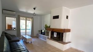 A living room with a black sofa, a white coffee table, a fireplace, and a view of the outdoors through large windows. - Top: Detached Villa for 8 People • Air Conditioning • Terrace • Beaches within a 10-minute walk (Saint-Cyr-sur-Mer)