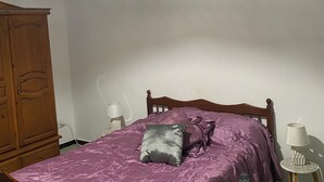 A bedroom with a wooden bed, purple bedding, a hanging lamp, a wooden wardrobe, and a bedside table with a lamp. - House with private pool close to town center (Houmet souk)