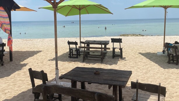 A beach with wooden tables and benches, and colorful umbrellas providing shade. - House with private pool close to town center (Houmet souk)