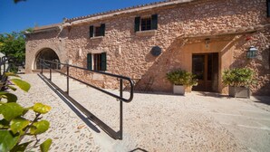 Un edificio in pietra con una scala che conduce all'ingresso, piante in vaso e un cielo azzurro intenso.