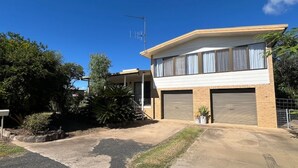 Ein zweigeschossiges Haus mit Garage, Satellitenschüssel und kleinem Garten.