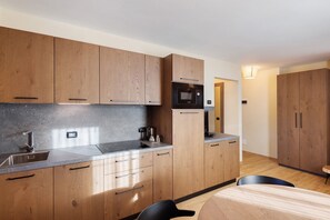 Cocina moderna con armarios de madera, un lavamanos de acero inoxidable y un microondas integrado.