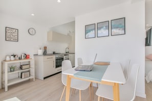 Una cocina moderna con armarios blancos, un fregadero y una zona de comedor con mesa y sillas.