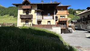 A multi-story building with balconies, a sign for 'Green Rose,' and a view of a hillside.