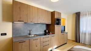 A modern kitchen with wooden cabinets, a granite countertop, a built-in oven, and a television.
