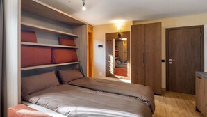 A bedroom with a bed, built-in shelving, a wardrobe, and a mirror.