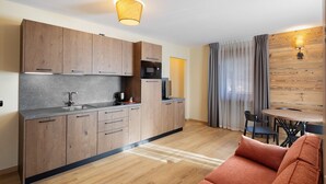 A modern kitchen with wooden cabinets, a microwave, and a sink. There is a dining area with a table and chairs.